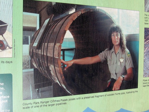 San Diego County Park Ranger shows a section of wooden flume pipe.
