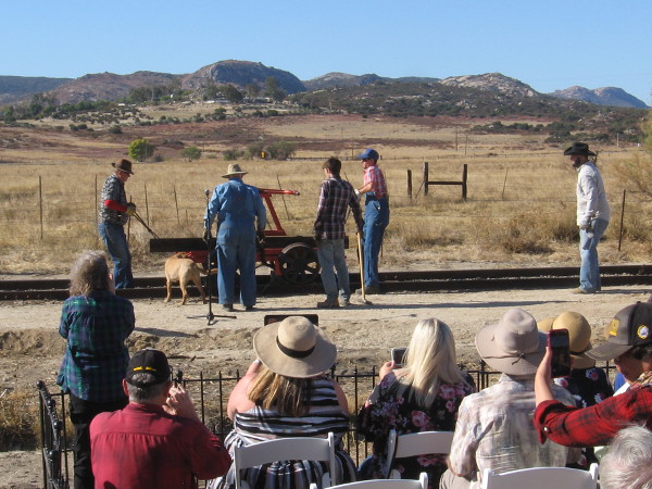 The railroad workers carry the last section of track to be laid.