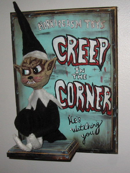 Creep in the Corner by artist Jennifer Cooksey. Mixed media sculpture and acrylic. A sinister Elf on the Shelf.