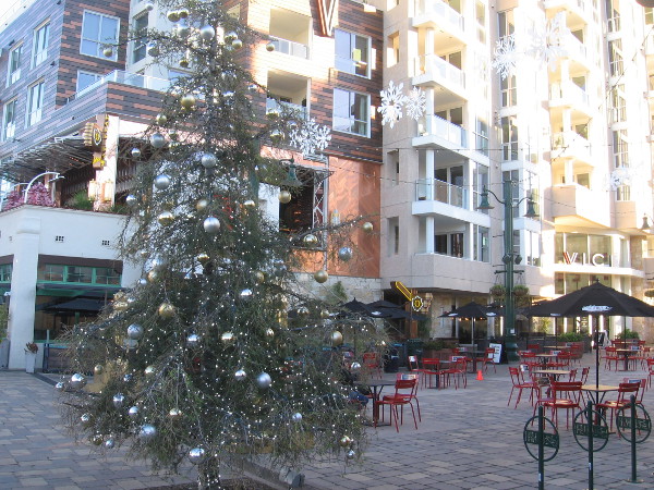 A silvery Christmas tree and white snowflakes near the piazza's many outdoor tables and chairs.
