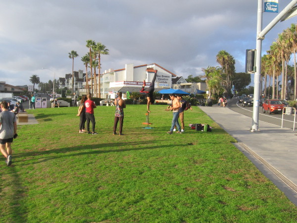 Someone performs a handstand in a grassy park that overlooks the beach in Carlsbad Village.