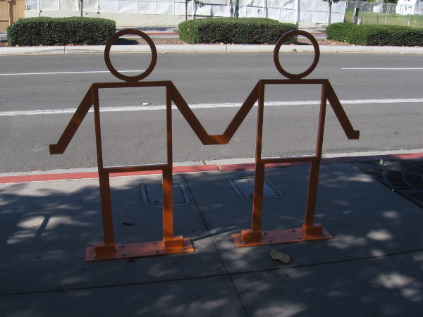 Sculpture of two people holding hands on sidewalk.