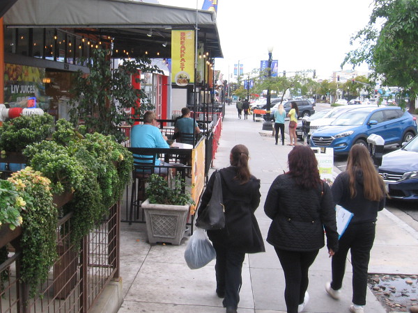 Some folks were out and about in Hillcrest, walking down the sidewalk or dining outdoors.