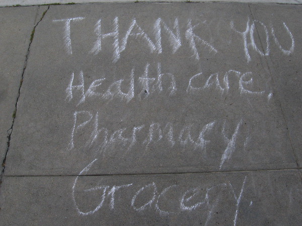 Written in chalk on the sidewalk: Thank you healthcare, pharmacy, grocery...