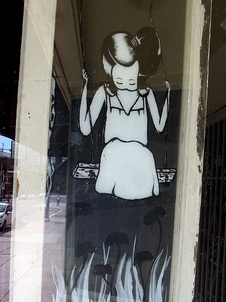 Art in a Bankers Hill window during the coronavirus pandemic. A girl on a swing...with a face covering.