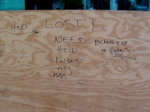Written on plywood by the sidewalk: Help. Lost! Need help finding my mind. Before it's too late.