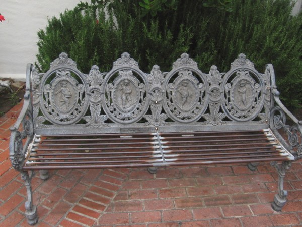 An ornate bench in the courtyard outside the rotunda of the Athenaeum Music and Arts Library. A small plaque on the bench reads In Memory of Genevieve Ferguson from Friends.