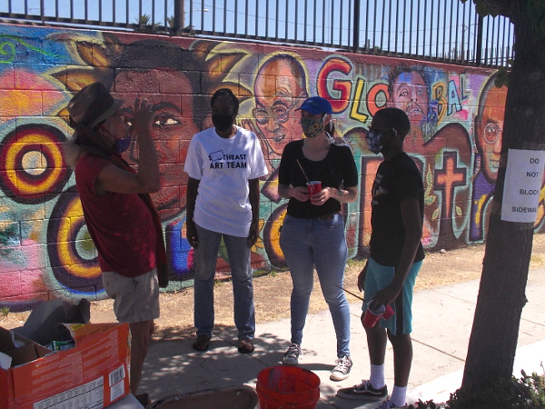 Internationally known muralist Mario Torero talks to local artists before commencing work restoring portions of his mural.