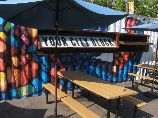 Colorfully painted shipping container by picnic benches indicates Quartyard is Your City Block.