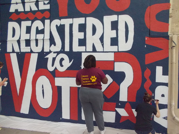 Community volunteers pitch in to help paint the inspiring mural.