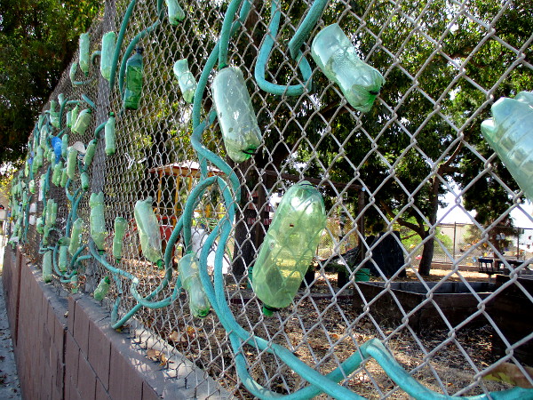 Recycled materials turned to art on the chain link fence.