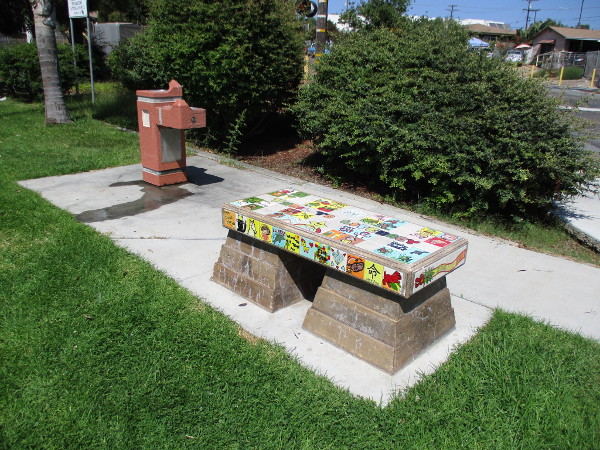 Trail to Literacy painted tile bench near a water fountain.