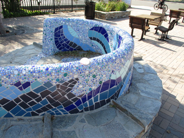 A beautiful blue mosaic tile bench curls like a river of water in Maple Street Plaza.
