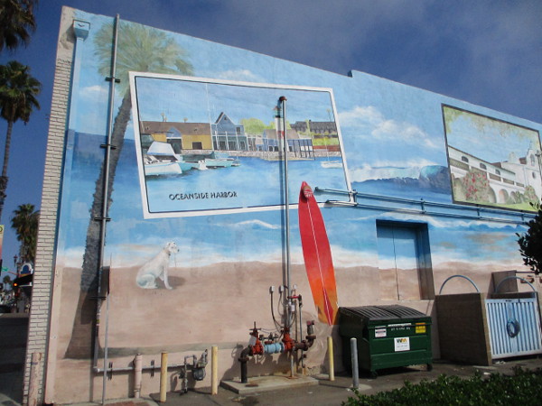 Large mural behind building at Pier View Way and North Coast Highway depicts Oceanside attractions as postcards.